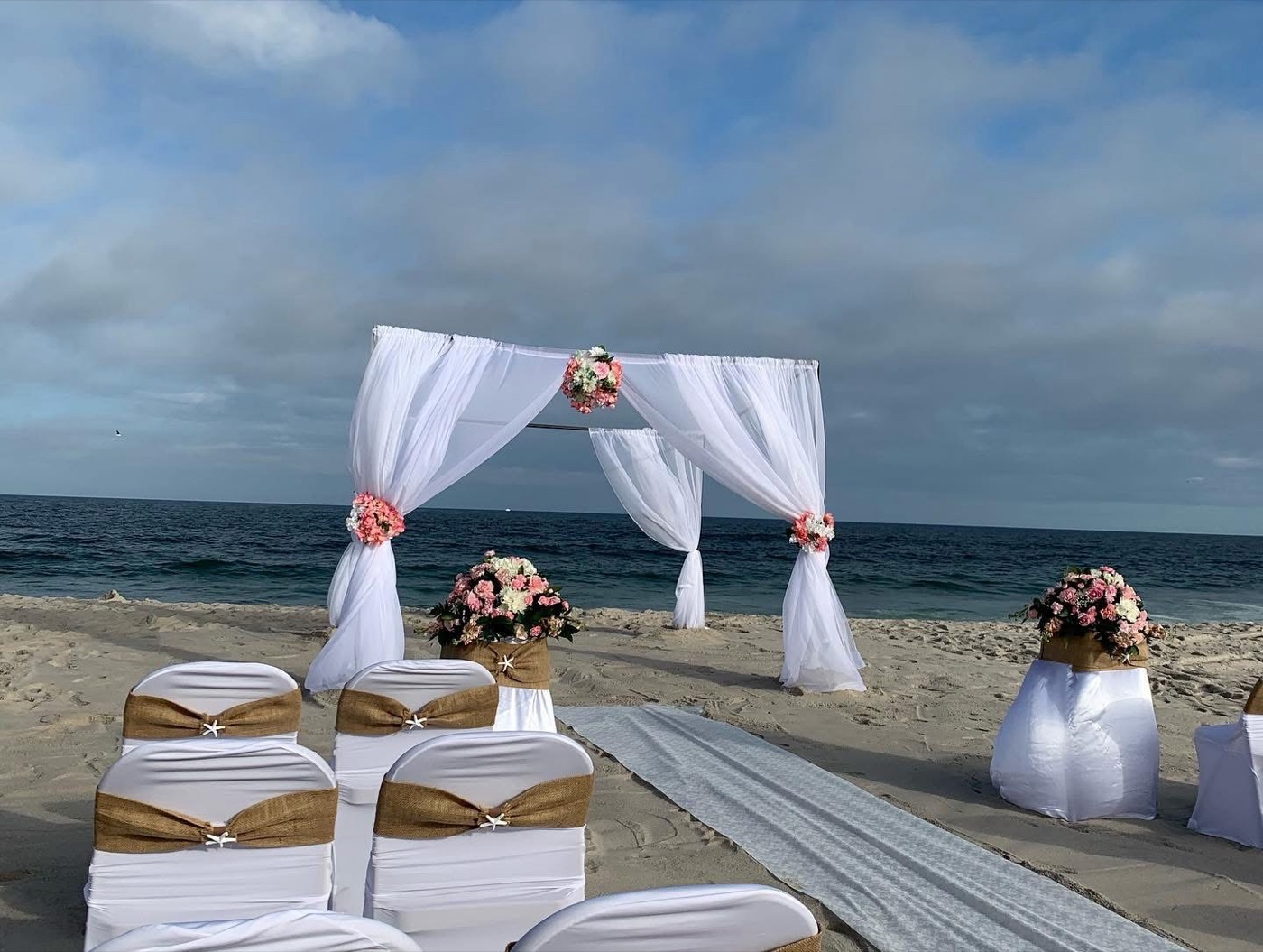 Beach ceremony arch with white flowers and ocean view