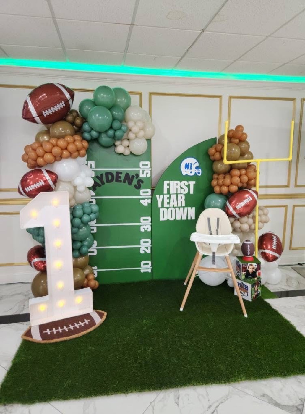 Football themed first birthday display with green balloons